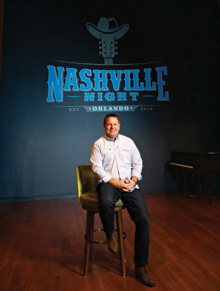 Jay Peeper sitting in front of a sign that says Nashville Night