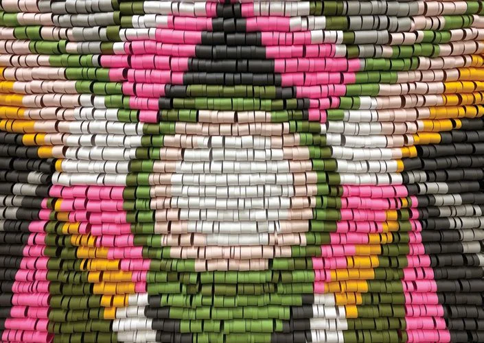 A woven art piece in greens, pinks, whites, peaches, and yellows