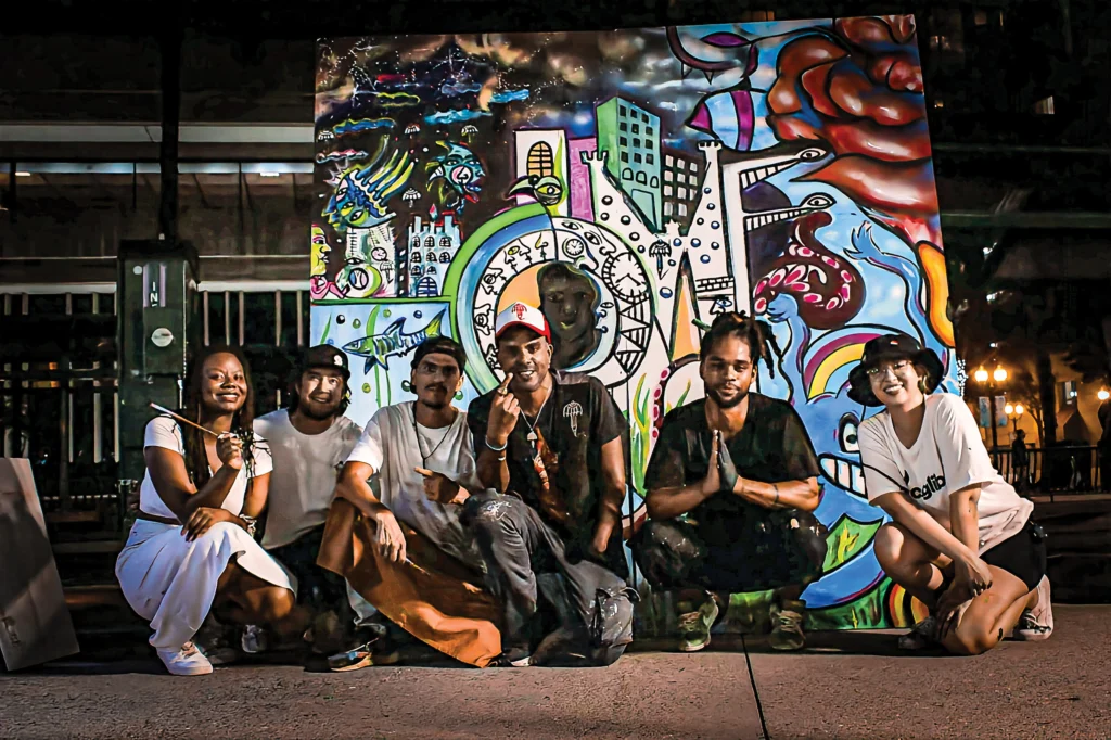A group of happy people sitting in front of a colorful impressionistic mural
