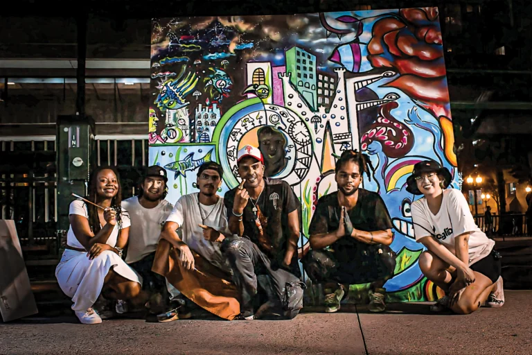 A group of happy people sitting in front of a colorful impressionistic mural