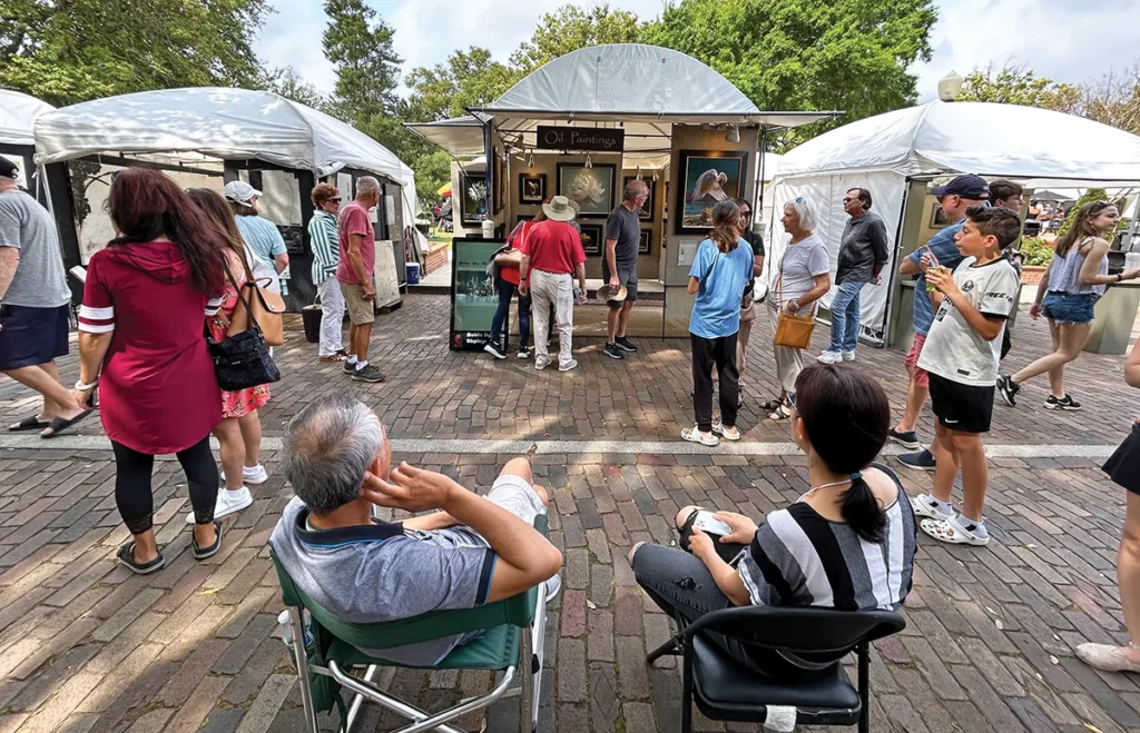 People sit in chairs and walk about at an outdoor festival