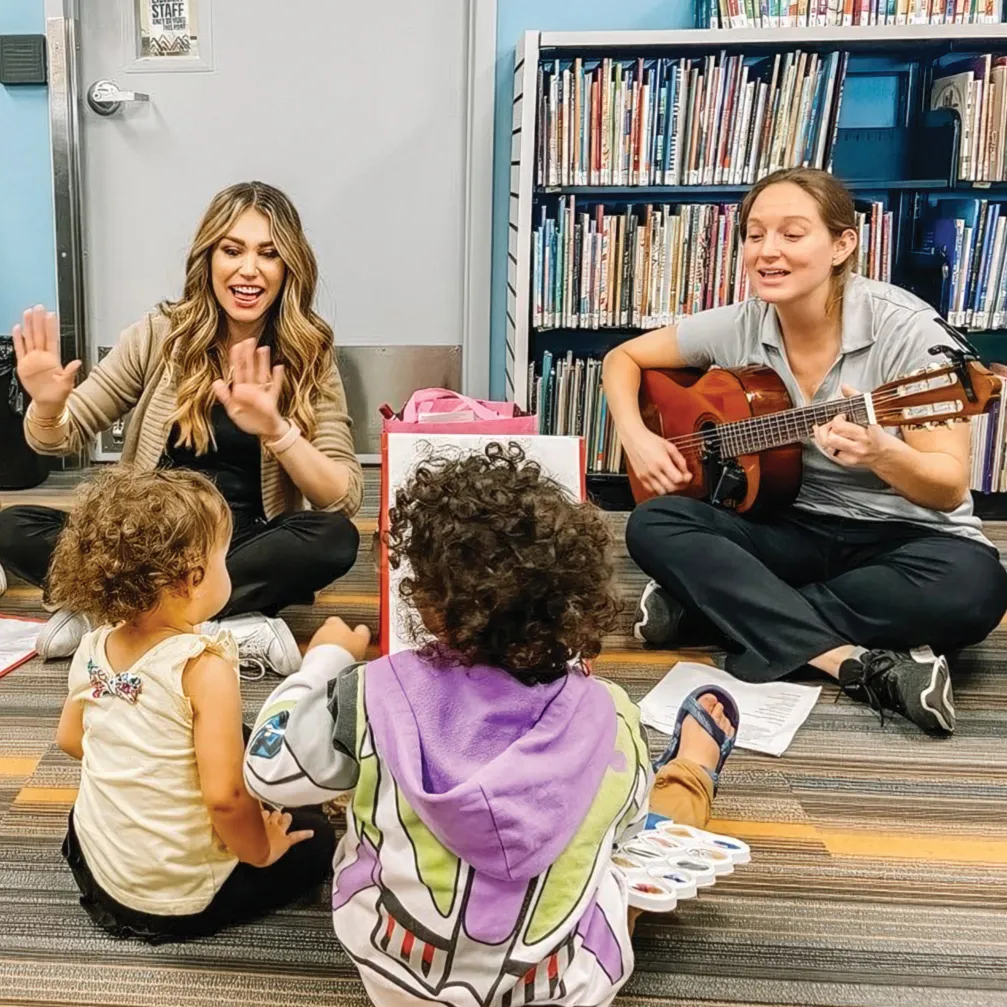 children and adults sing and play instruments