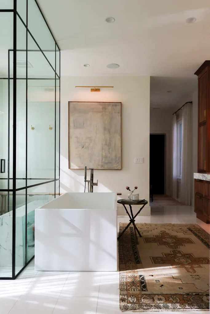 Light streams into the master bathroom through a wall of glass windows