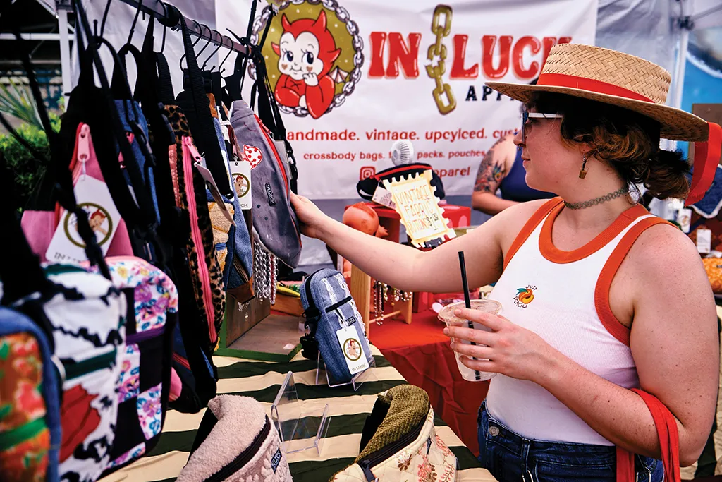 A person looking at bags displayed on a festival stall