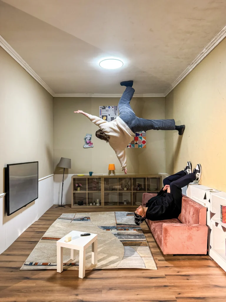 People walk and sit in a room that appears to be turned on its side