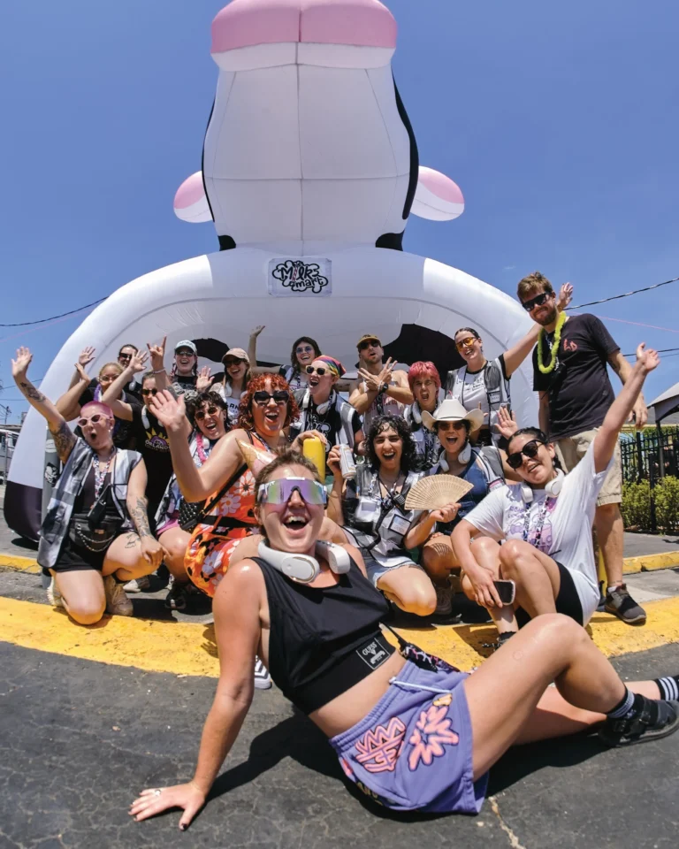 A group of happy people pose in front of a large inflatable cow
