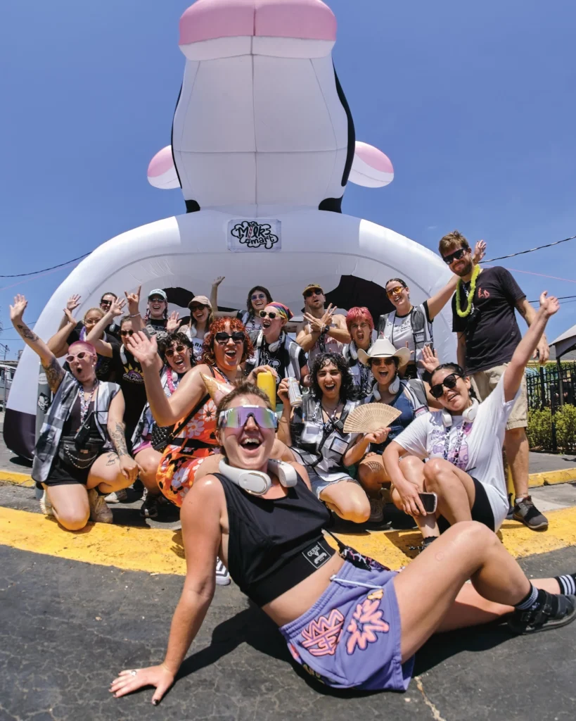 A group of happy people pose in front of a large inflatable cow