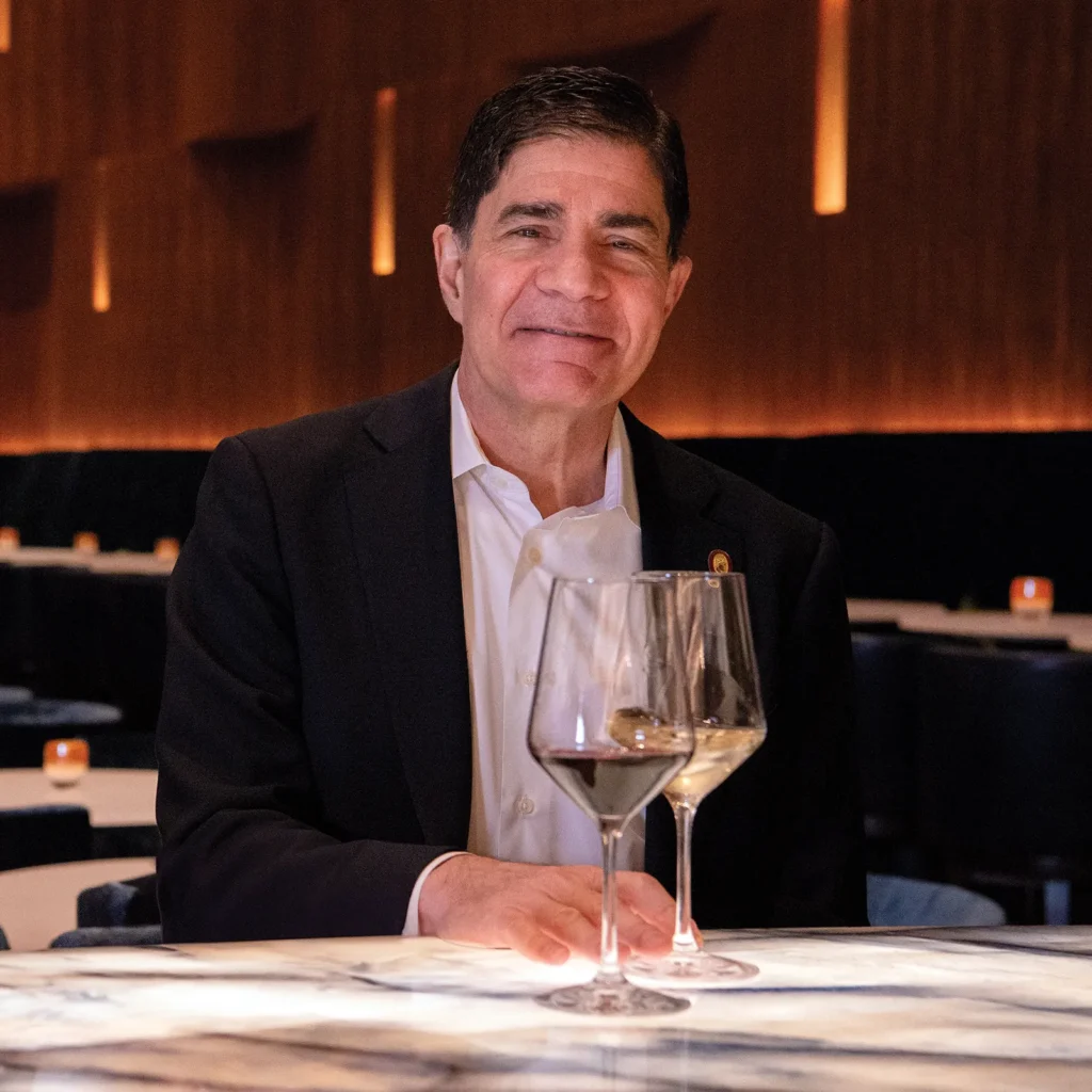 George Miliotes holding a glass of wine
