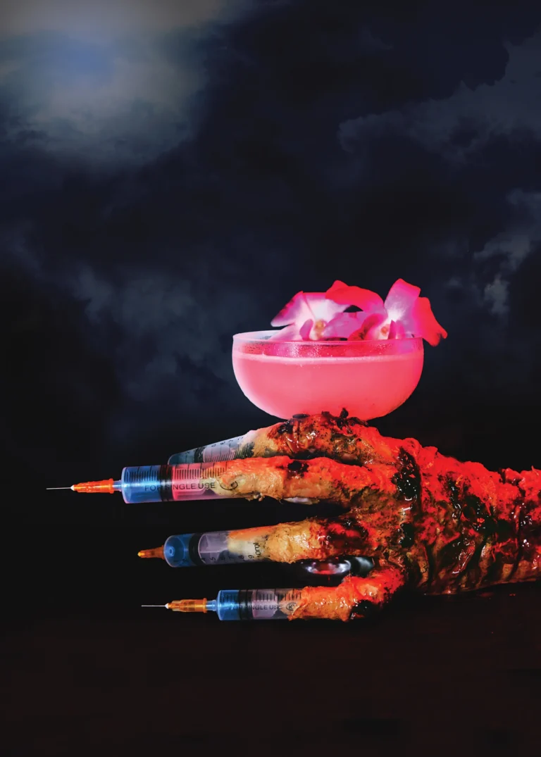 A creepy hand made of syringes holding a colorful cocktail
