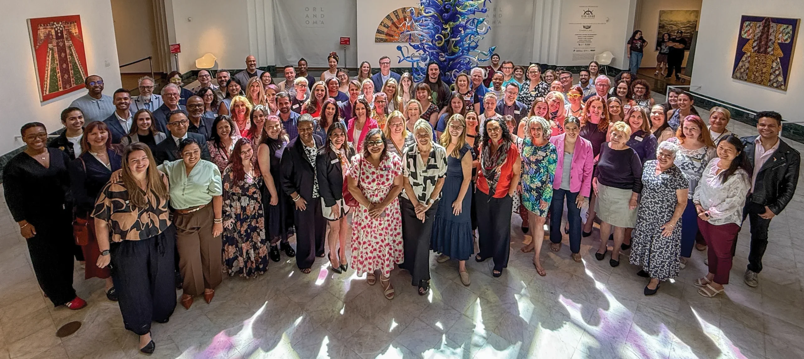 A large group of people standing together in room full of art.