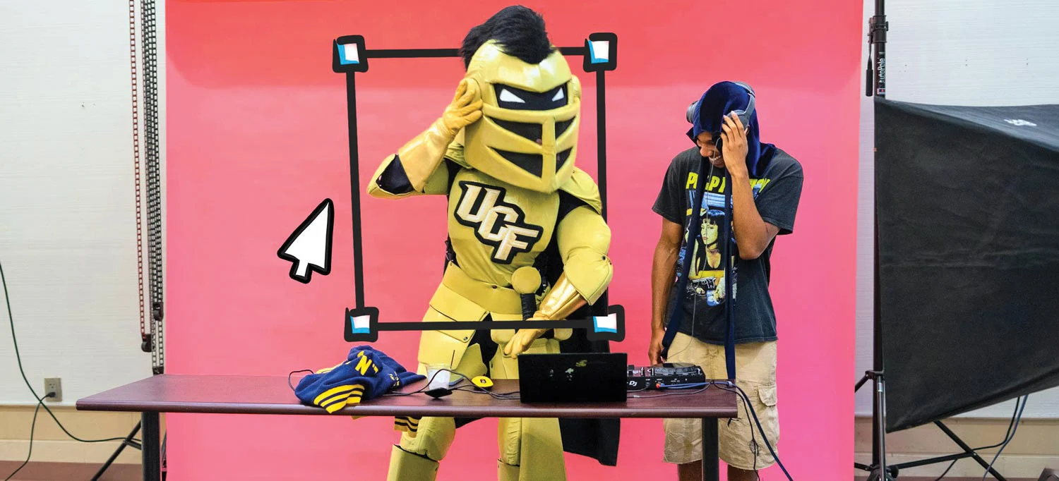 Knightro, the UCF mascot, at a demonstration table beside a student wearing a headset in front of a pink backdrop