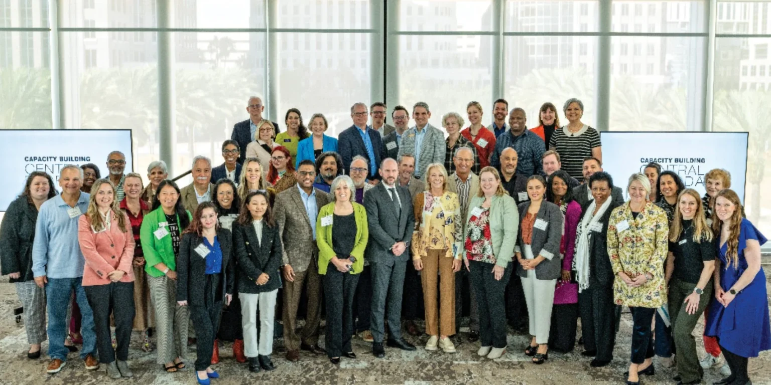 Large group of arts nonprofit leaders posing together in a bright room