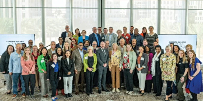 Large group of arts nonprofit leaders posing together in a bright room