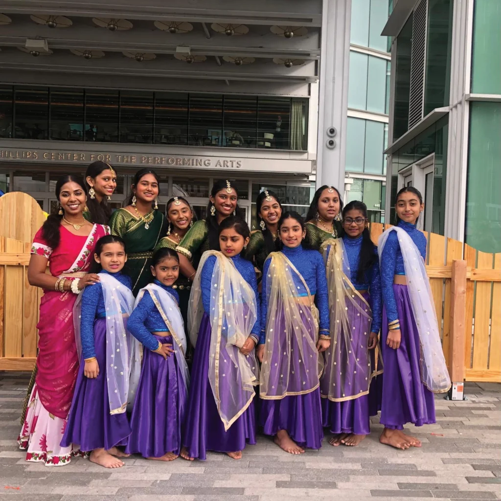 Young dancers in purple and blue South Asian costumes posing outdoors at FusionFest