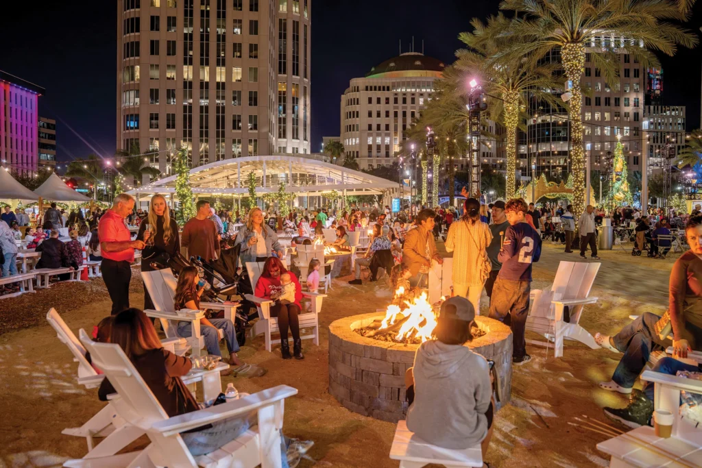 Families around a fire pit on Seneff Arts Plaza at night during the Frontyard Holiday Festival