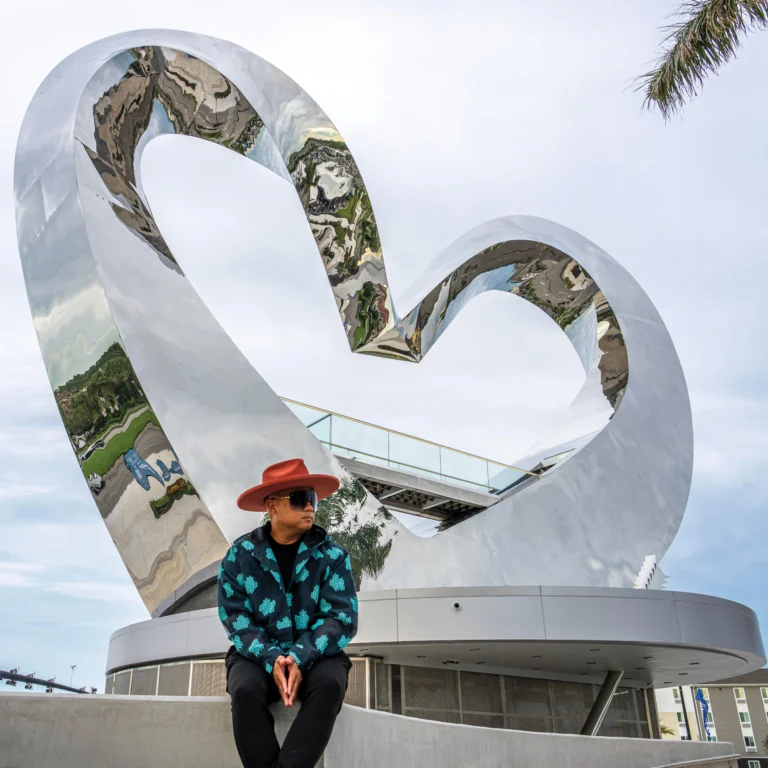 JEFRË seated in front of his towering mirrored heart sculpture