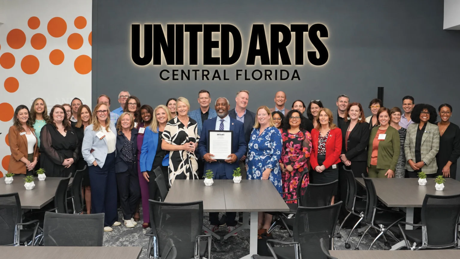 Mayor Jerry L. Demings holding an award, surrounded by United Arts of Central Florida staff and board members