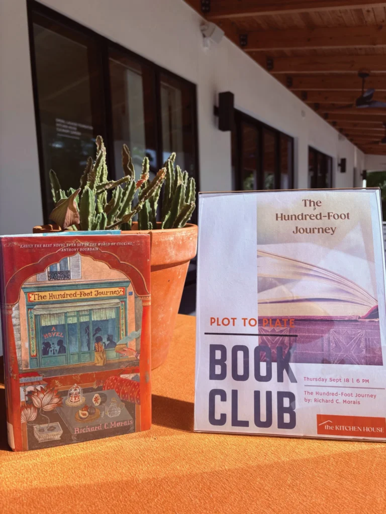 Plot to Plate Book Club sign beside a copy of The Hundred-Foot Journey